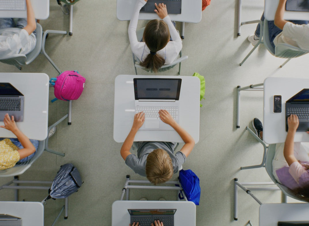 Overhead view of pupils at exam desks with laptops